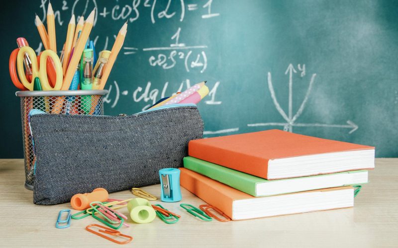 Back to school - blackboard with pencil-box and school equipment on table