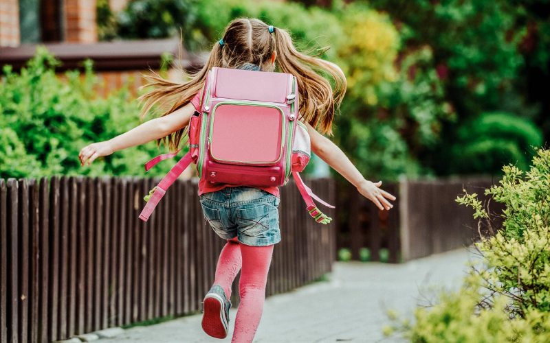 little girl with a backpack run  to school. back view