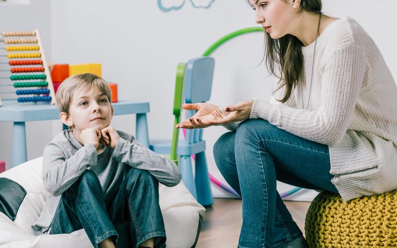 Helpful professional young psychologist trying to get through to little boy with problems