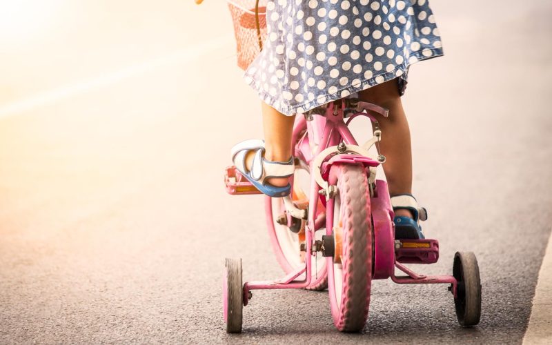 Child cute little girl riding bike in park