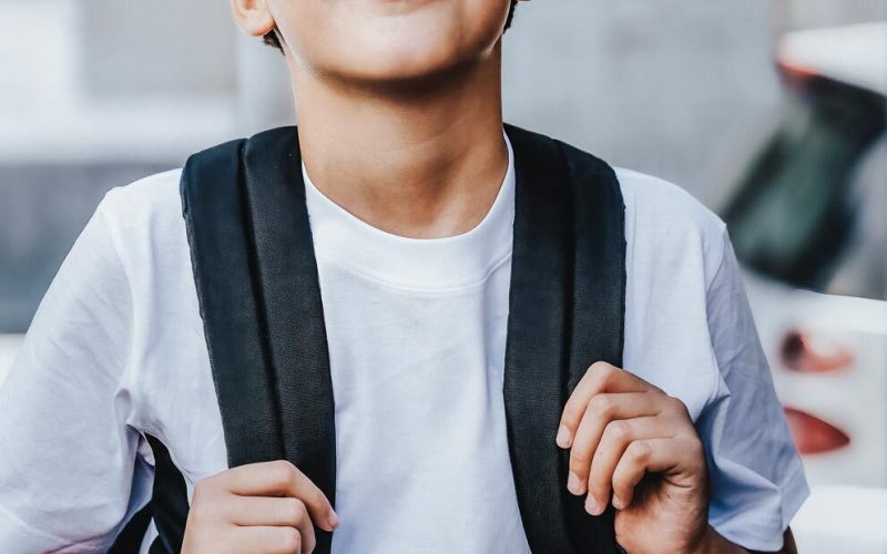 Cute handsome schoolboy with backpack going to school, urban street portrait - people lifestyle concept