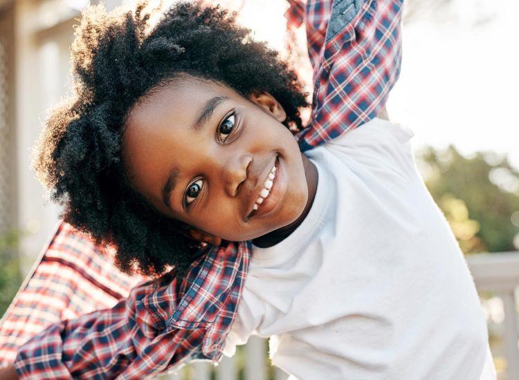 Portrait of a cheerful little boy playing around while looking into the camera outside during the day