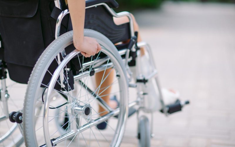 A girl with a broken leg sits in a wheelchair