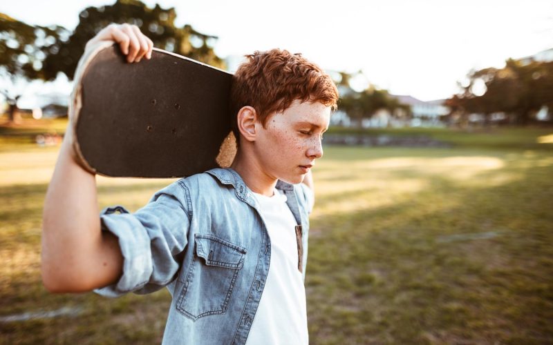 sad kid with the skateboard on the shoulder
