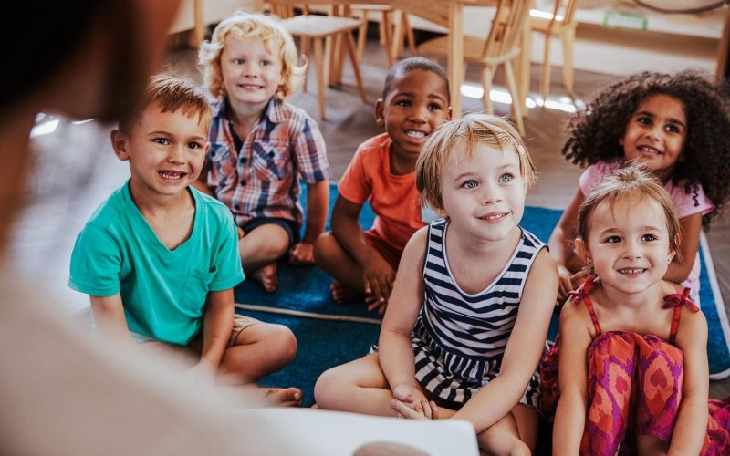 Teacher At Montessori School Reading To Children At Story Time