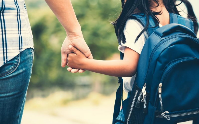 Back to school. Cute asian pupil girl with backpack holding her mother hand and going to school in vintage color tone