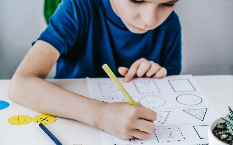 Boy focusing on his homework while sitting at desk.