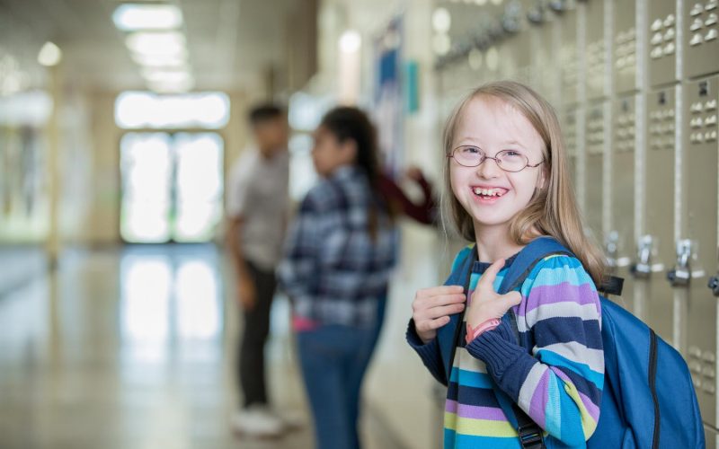 Adorable little girl with Down Syndrome smiles on her first day of Junior High School
