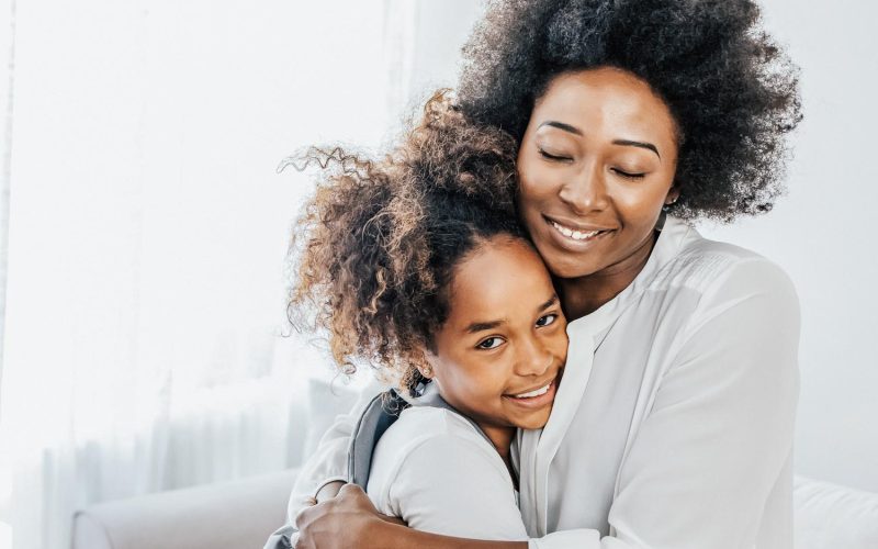 Mother taking daughter to school. Black woman in front hallway fixing young girls dress. Mother and daughter preparing the first day going study back to school. Student concept