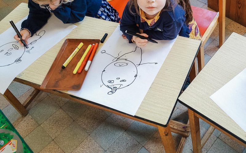 Wilsele, Flemish Brabant, Belgium - February 15, 2022: caucasian preschoolers age 3, in a real situation school kindergarten classroom learning  facial expressions by drawing clowns.