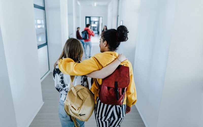 Rear view of young high school students walking in corridor at school, back to school concept.