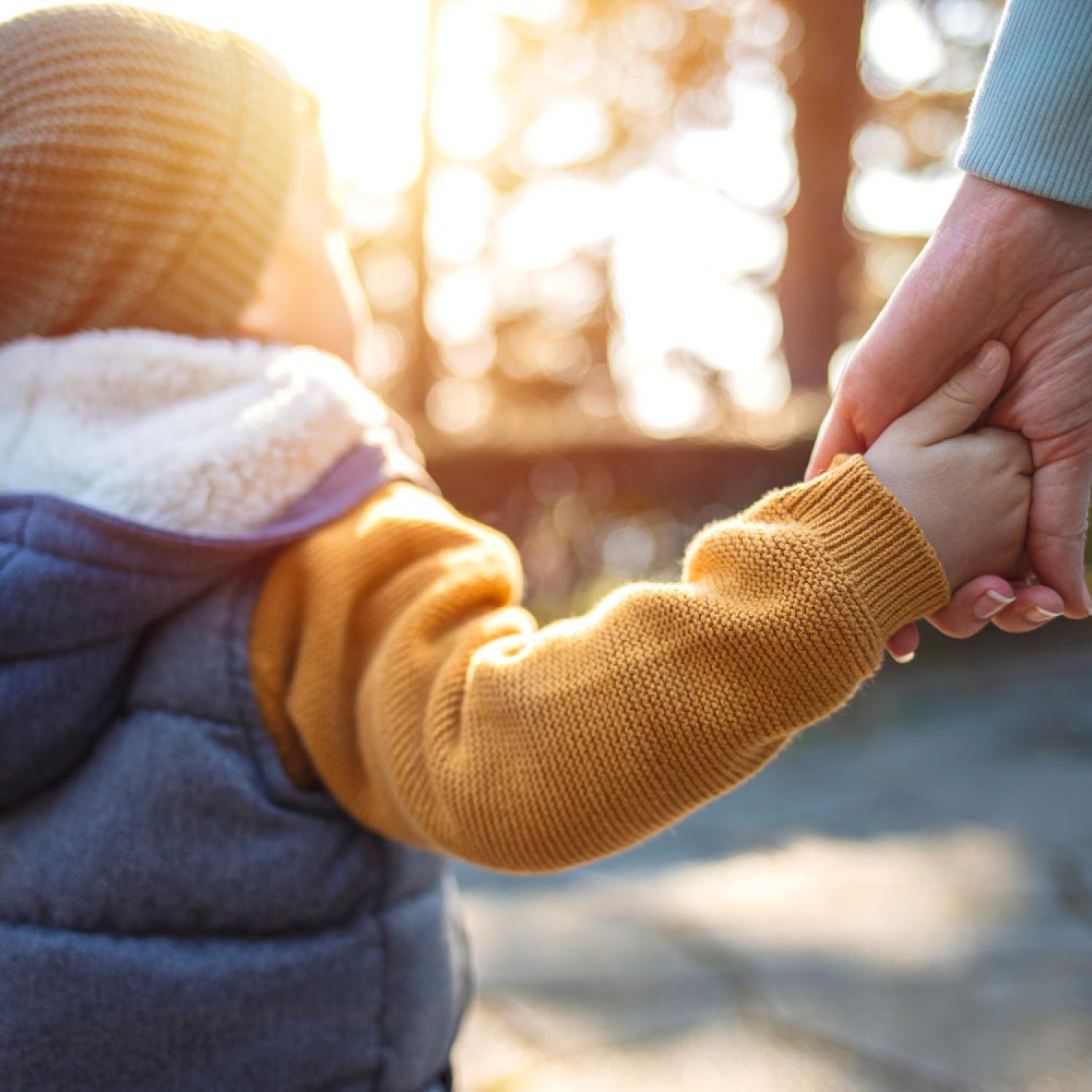 Close up of mother and a child hands at the sunset. A parent holds the hand of a small boy in the sunset. Mother holding her little boys hand walking down the street