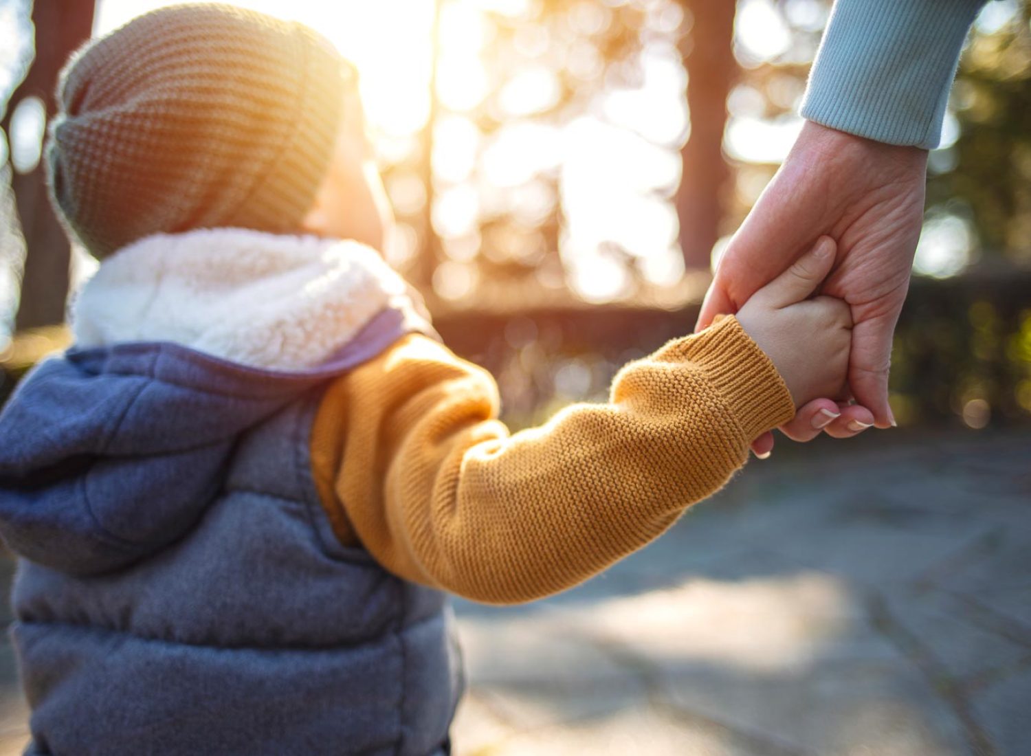 Close up of mother and a child hands at the sunset. A parent holds the hand of a small boy in the sunset. Mother holding her little boys hand walking down the street
