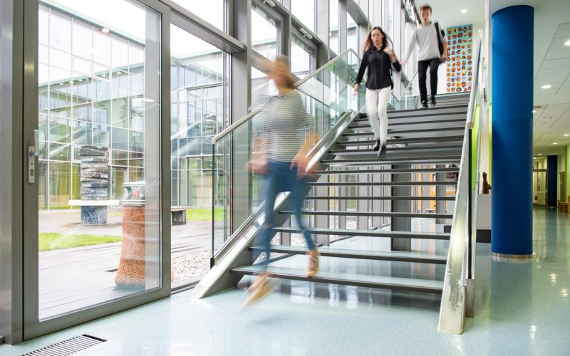 High school students walking on stairs between lessons in college building