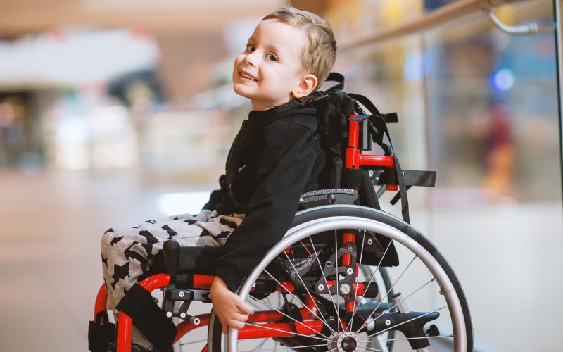 Cute little boy in wheelchair in shopping mall