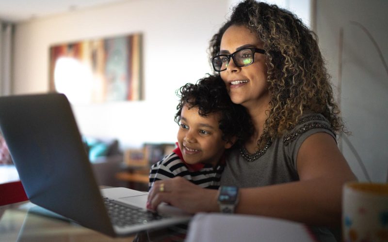 Mature woman working at home, carrying young son