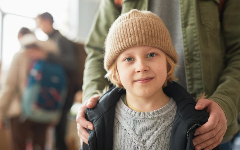 Close up of Caucasian young boy with dad looking at camera at help center for refugees, copy space