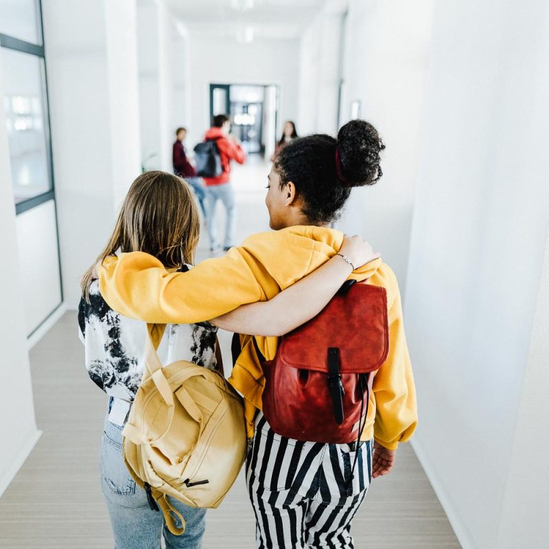 Rear view of young high school students walking in corridor at school, back to school concept.