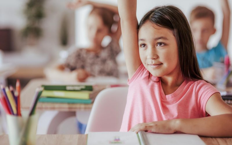 Teenage student raising hand in classroom