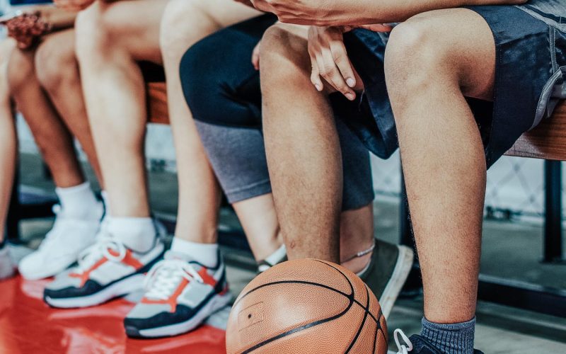 Group of young teenager friends on a basketball court relaxing using smartphone addiction concept