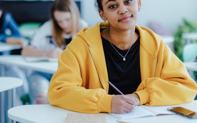 High school students paying attention in class, sitting in their desks and writing notes, back to school concept.