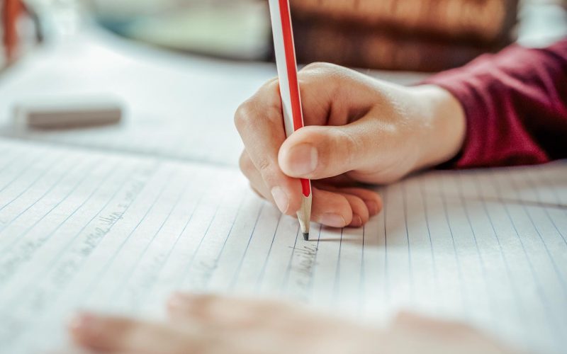 Boy writing in a notepad doing his school work spelling or homework
