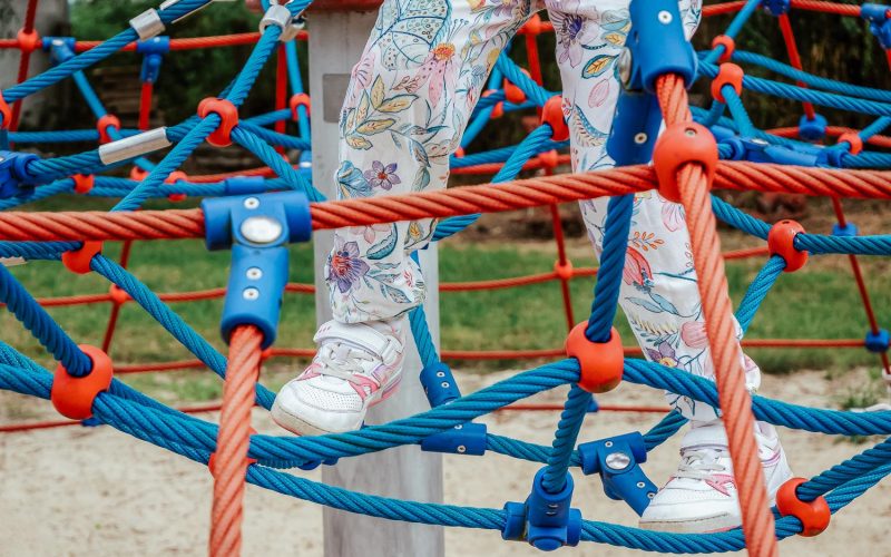 Anonymous child, active elementary school age girl climbing, walking on ropes legs closeup, playground, healthy outdoor activities, leisure and recreation, physical exercise simple concept, one person