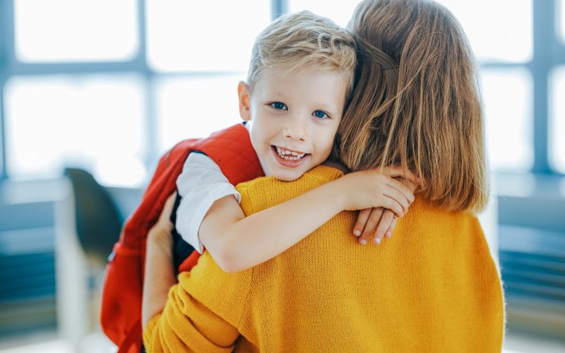 First day at school.  Cheerful child   schoolboy   hugs his mother before the first day at school at home