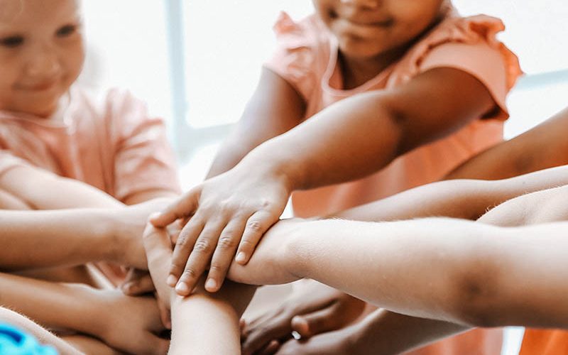 Little children putting their hands together, closeup. Unity concept