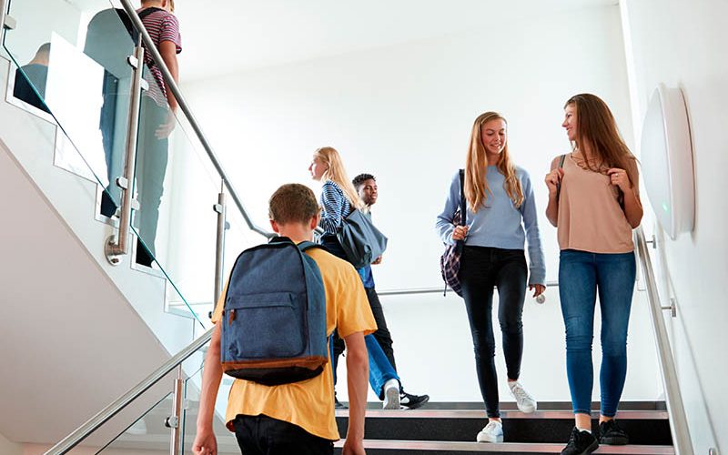High School Students Walking On Stairs Between Lessons In Busy College Building