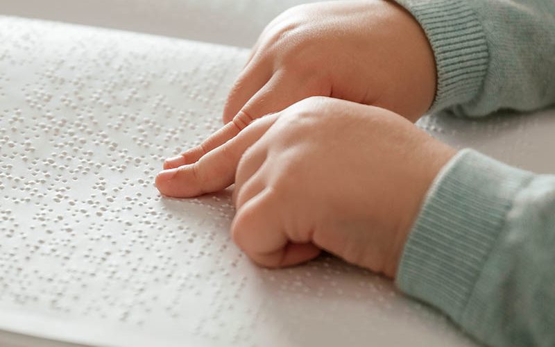 Blind child reading book written in Braille, closeup