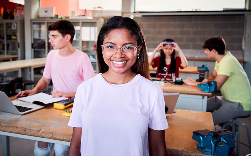 Portrait of a girl standing in a technology class looking at the camera. Vocational training students in the classroom studying electronics, robotics, electricity or some kind of technical college