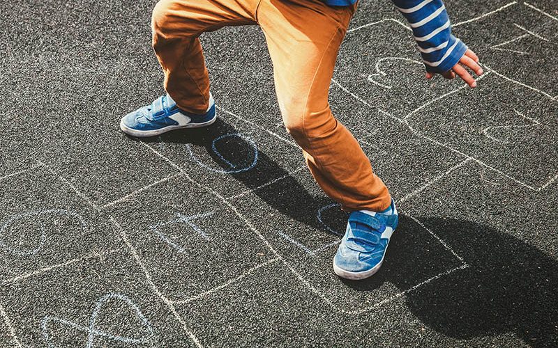 little boy playing hopscotch on playground