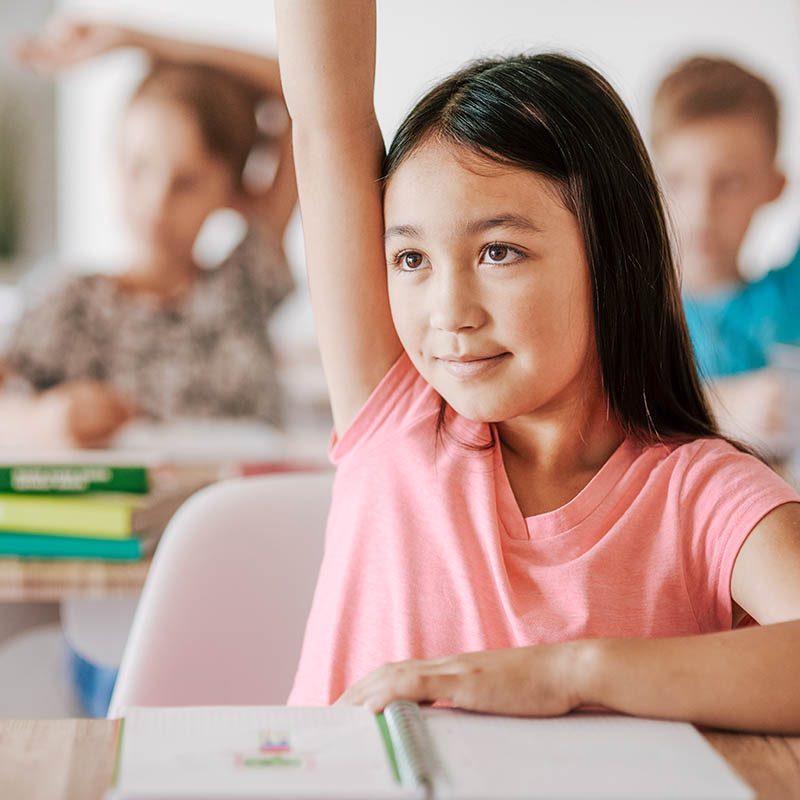 Teenage student raising hand in classroom